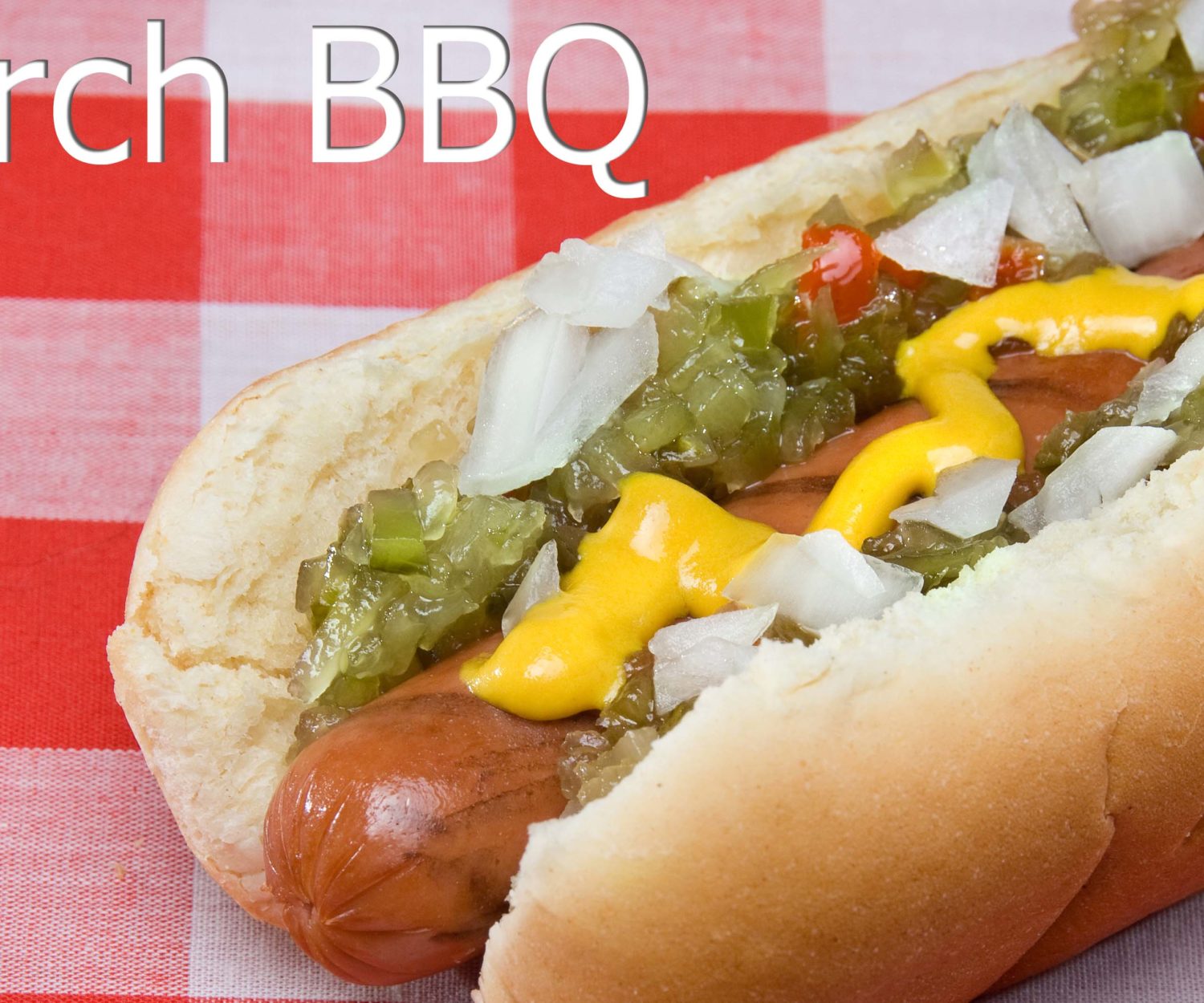 A scrumptious barbecued hotdog with relish, onions, mustard and ketchup rests on a picnic table waiting to be consumed.