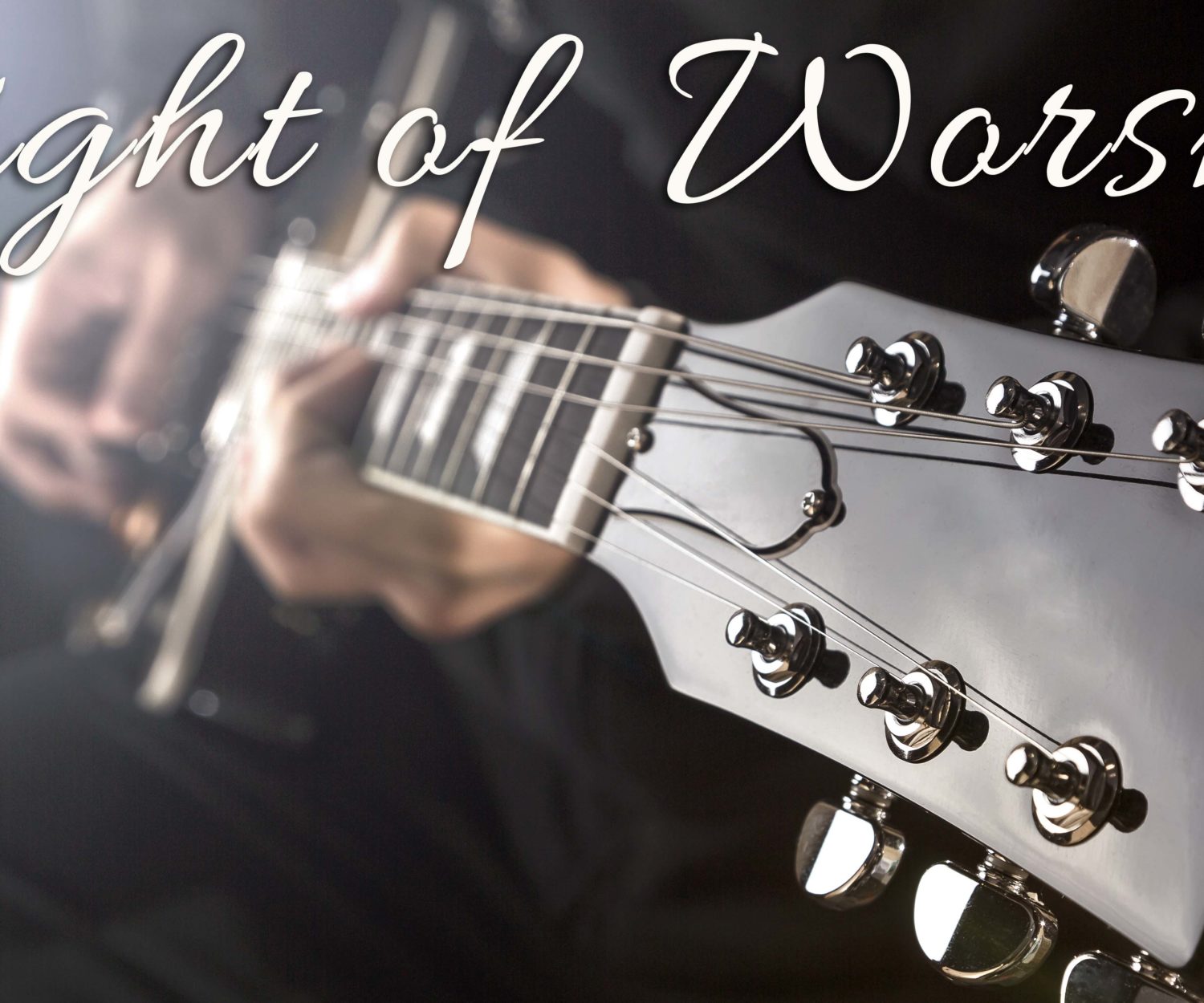 Close up of a man playing a guitar with spot light behind.