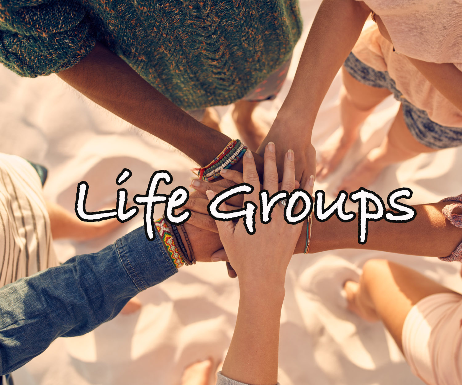 Group of young men and women showing unity. Group of young friends putting their hands together at the beach.